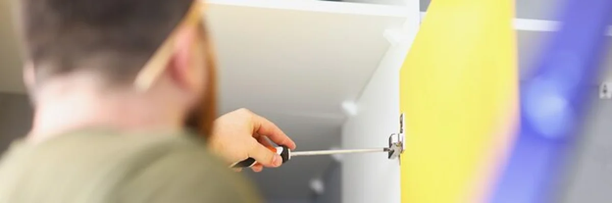 Mężczyzna stolarz dokręca uchwyt w szafce