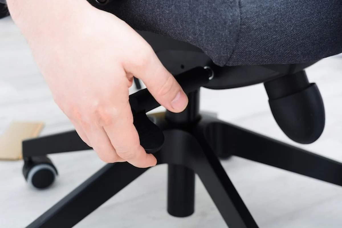 Mężczyzna sprawdza mechanizm krzesła biurowego