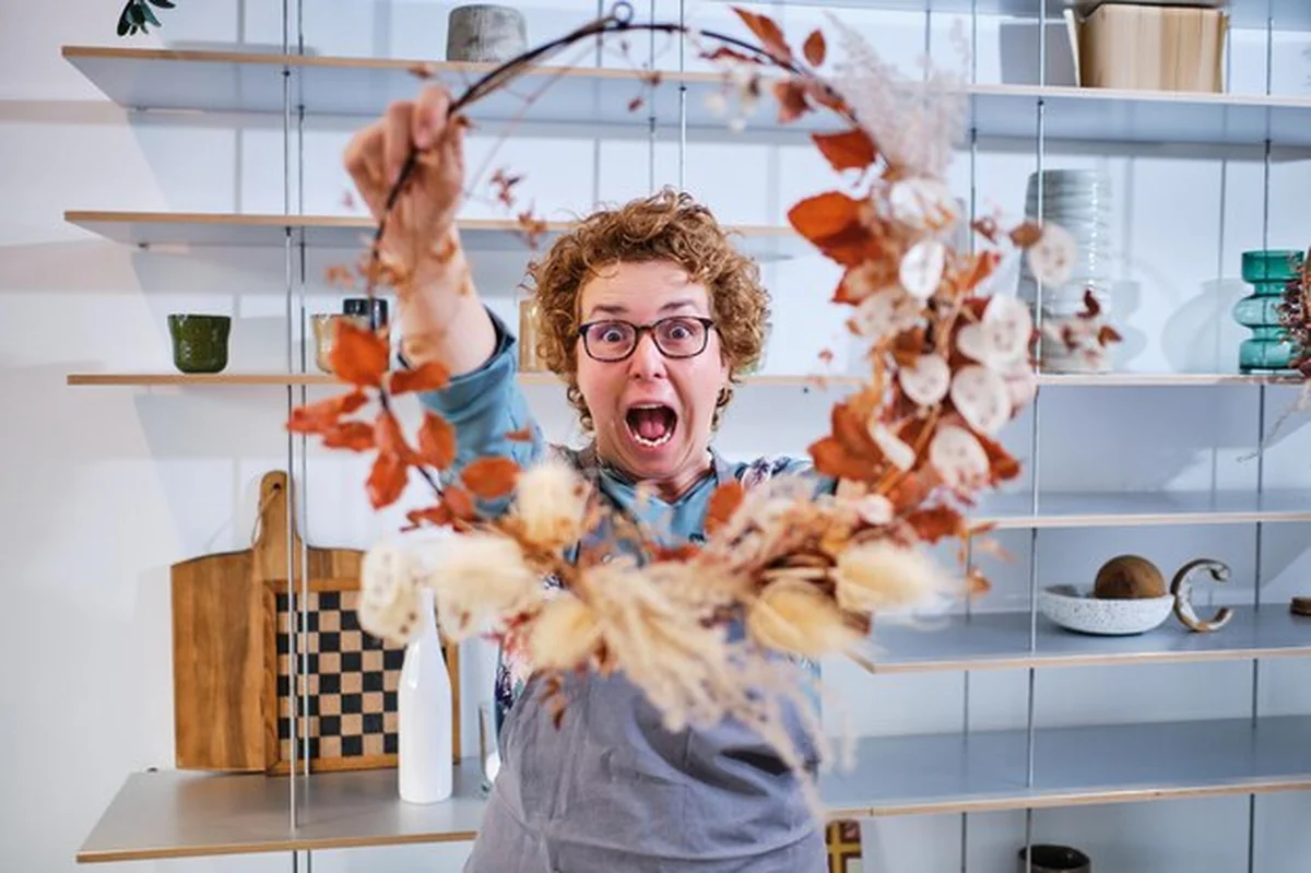 Zdziwiona kobieta w średnim wieku trzymająca wieniec z liśćmi