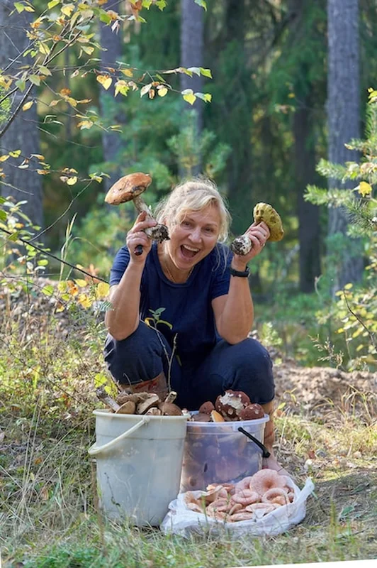 Dziewczyna trzyma duże borowiki przed wiadrami z grzybami