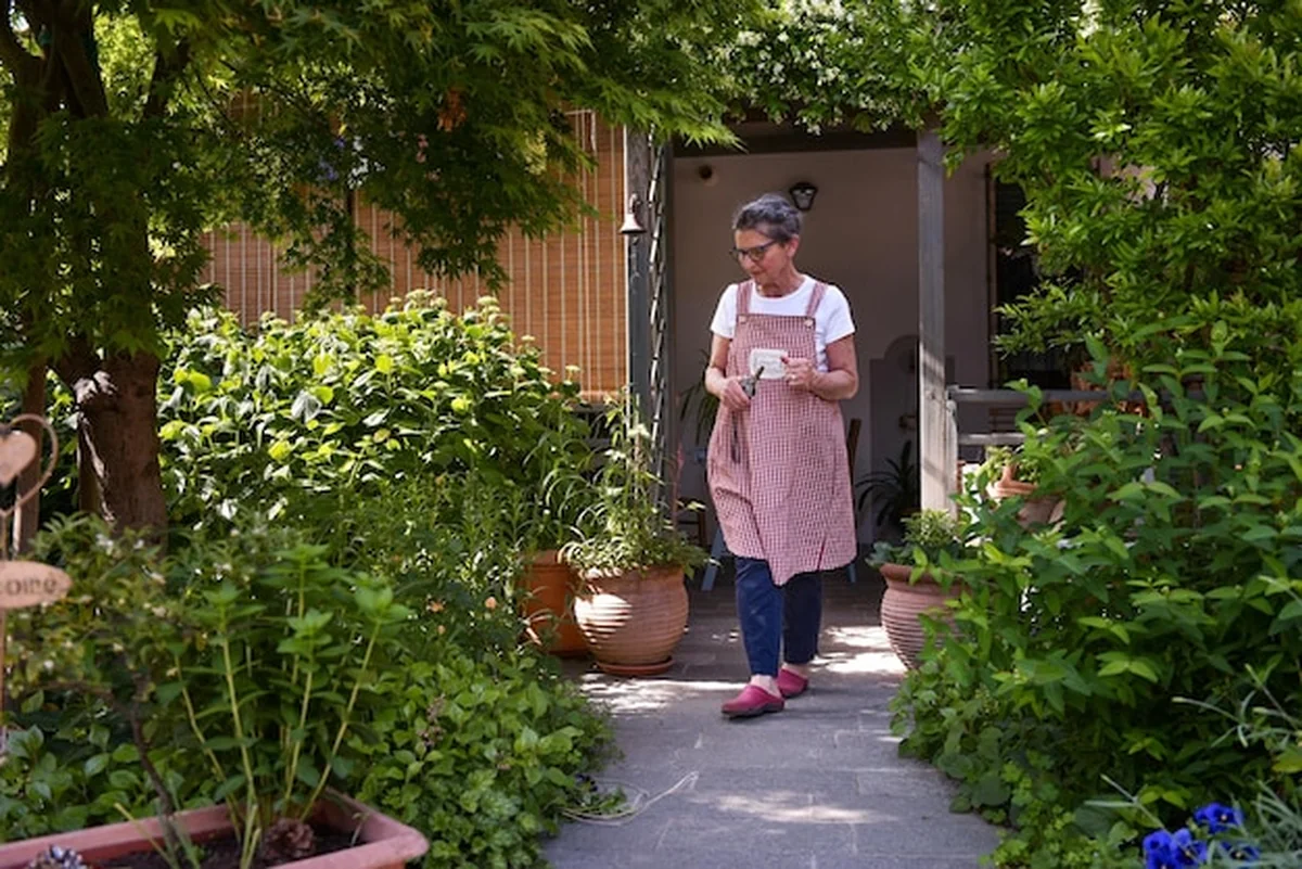 Dojrzała kobieta w ogrodzie patrząca na rośliny