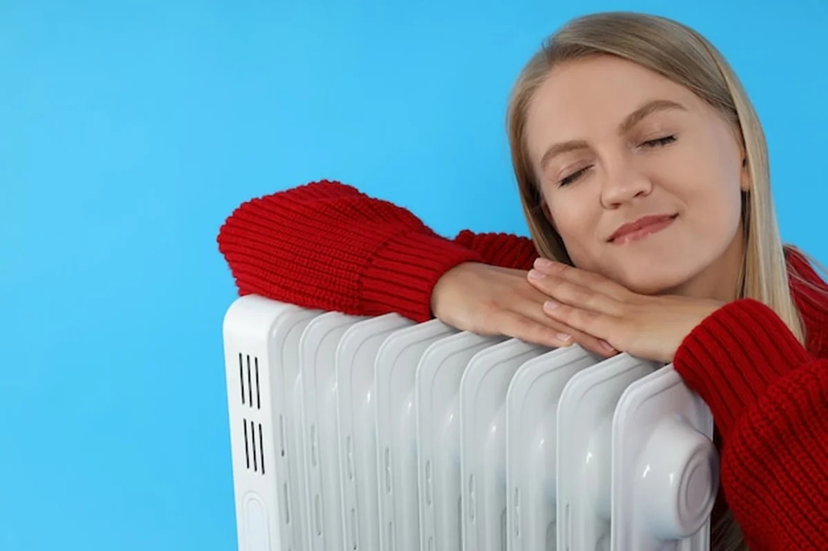 Kobieta trzymająca grzejnik przed niebieskim tłem