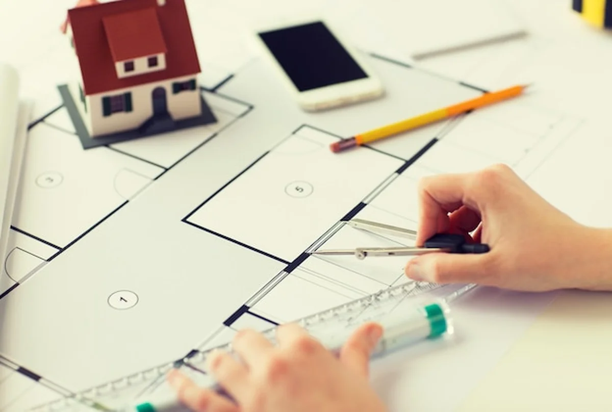 Architekt mierzy plan domu mieszkalnego z kompasem i linijką