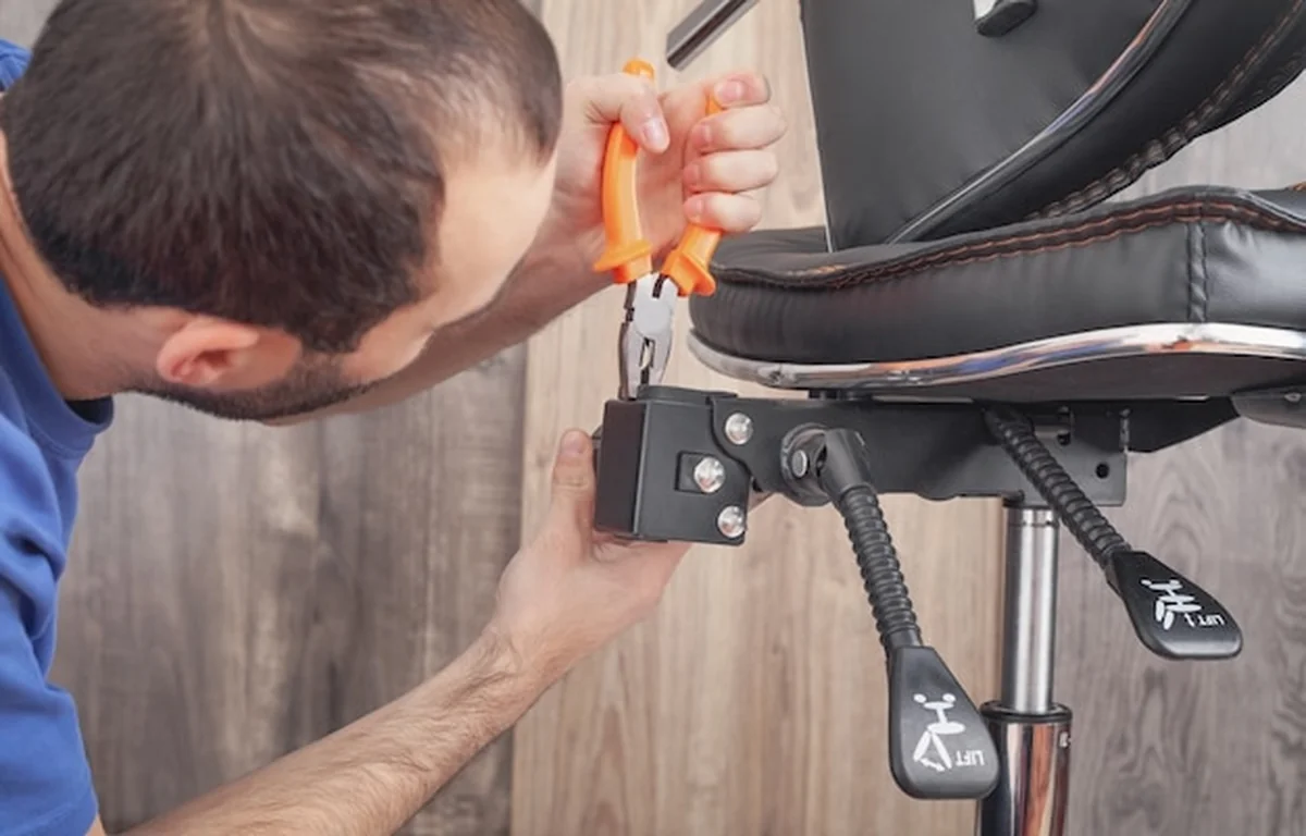 Kaukaski mężczyzna naprawia krzesło biurowe